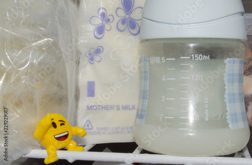 lot of frozzen breast milk in storage bags stored in the freezer and baby bottle with fresh expresed breastmilk photo