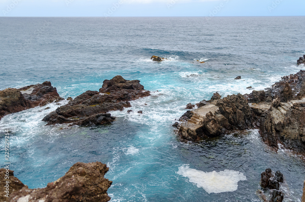 rocky coastline, natural volcanic rock, foaming water