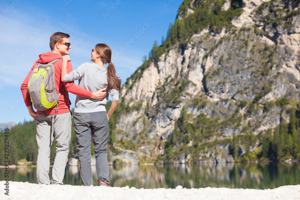 Hikers with backpacks sitting on top of a hill and enjoying mountains view. Dolomiti, Alta Badia Hikers with backpacks sitting on top of a hill and enjoying mountains view. Dolomiti, Alta Badia