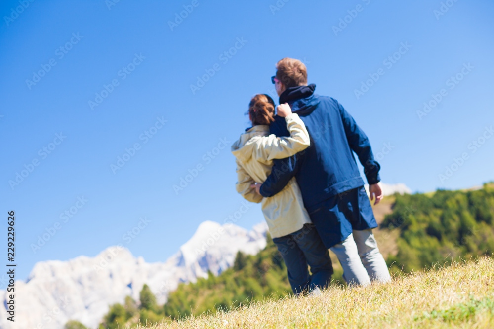 Hikers with backpacks sitting on top of a hill and enjoying mountains view. Dolomiti, Alta Badia