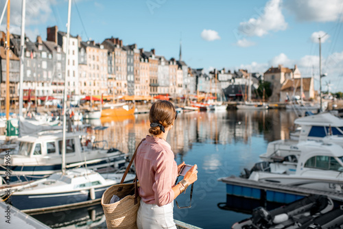 Young woman tourist enjoying beautiful view on the harbour traveling in Honfleur town in Normandy, France