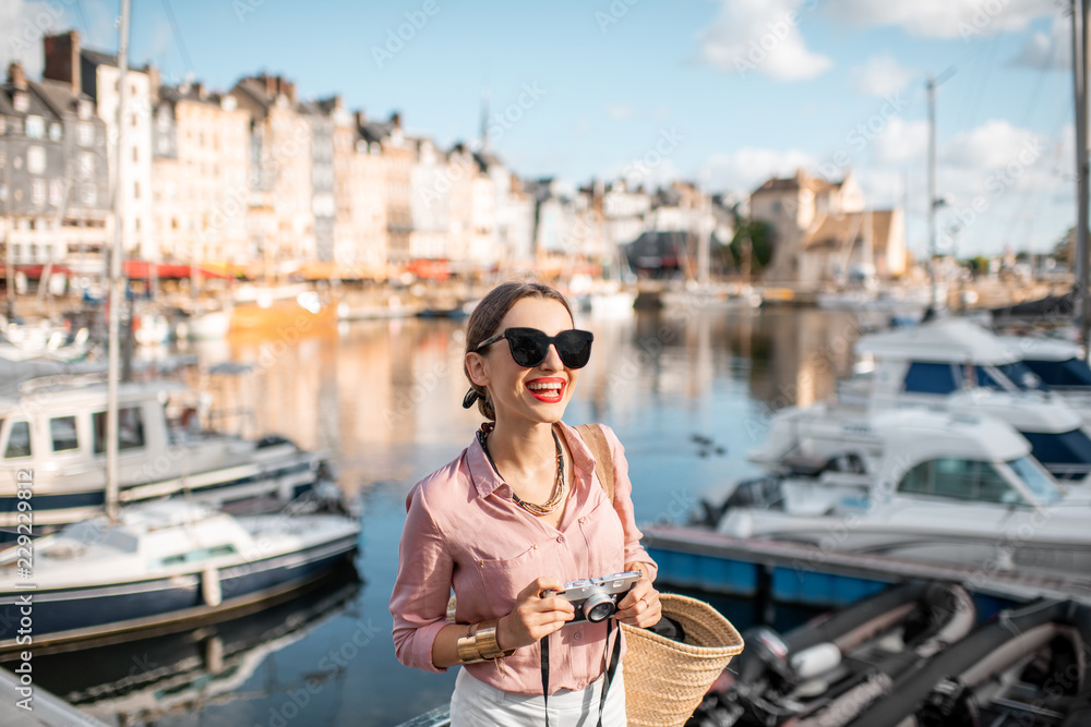 Obraz premium Young woman tourist enjoying beautiful view on the harbour traveling in Honfleur town in Normandy, France
