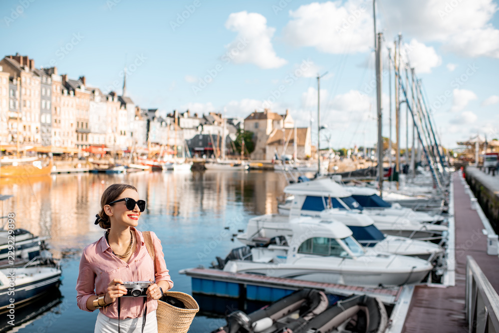 Young woman tourist enjoying beautiful view on the harbour traveling in Honfleur town in Normandy, France