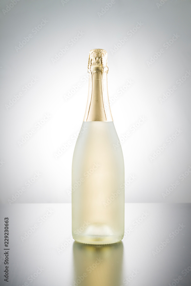 Bottle of champagne on a reflective surface with white gradient background. Bottle of champagne on a reflective surface with white gradient background.