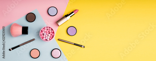 Makeup products and decorative cosmetics on color background flat lay. Fashion and beauty blogging concept. Long web format for banner