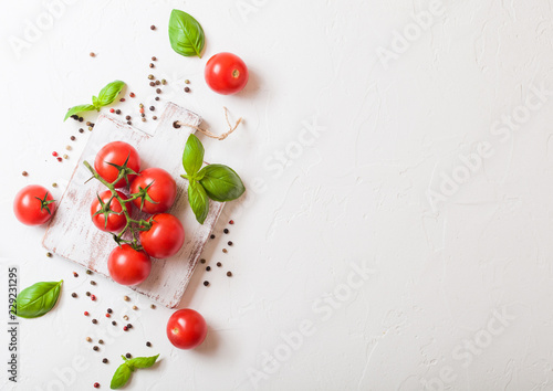 Organic Cherry Sugardrop Tomatoes on the Vine with basil and pepper on chopping board on stone kitchen background. Space for text