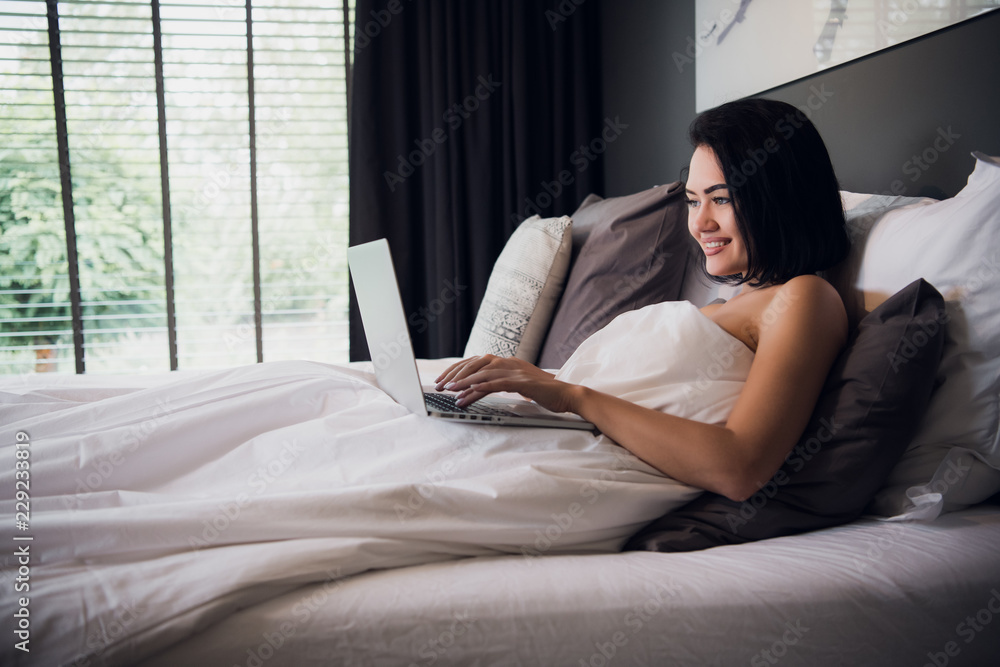 Young woman at home sitting on bed woke up browsing laptop Young woman at home sitting on bed woke up browsing laptop
