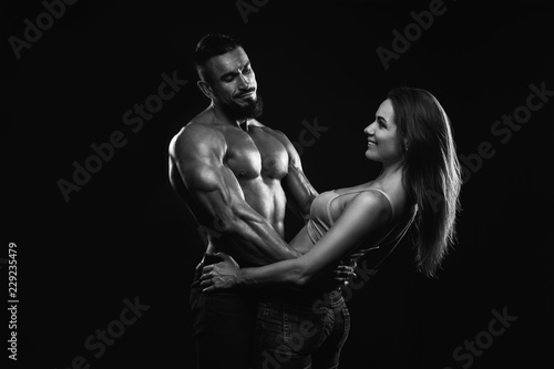 Fitness couple on a black background are in the studio. Black and white