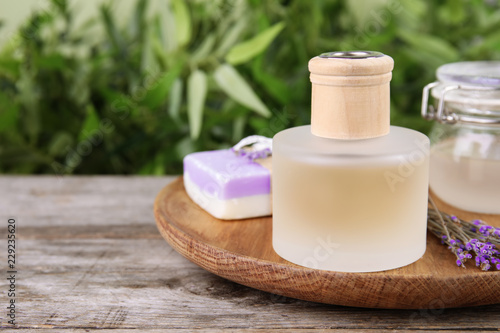 Fototapeta Naklejka Na Ścianę i Meble -  Natural herbal oil and lavender flowers on table against blurred background. Space for text