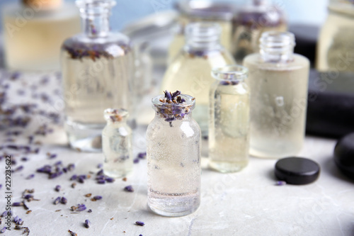 Fototapeta Naklejka Na Ścianę i Meble -  Bottles with natural herbal oil and lavender flowers on color table, closeup