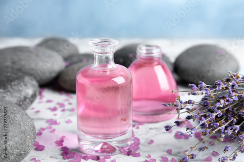 Fototapeta Naklejka Na Ścianę i Meble -  Natural herbal oil and lavender flowers on table against blurred background