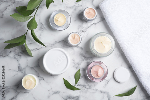 Flat lay composition with hand cream jars on marble background
