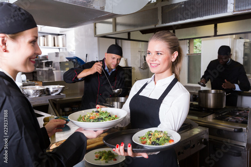 Waitress taking cooked meals from chef