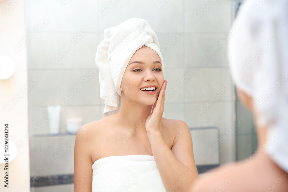 Beautiful woman with clean towels near mirror in bathroom Beautiful woman with clean towels near mirror in bathroom