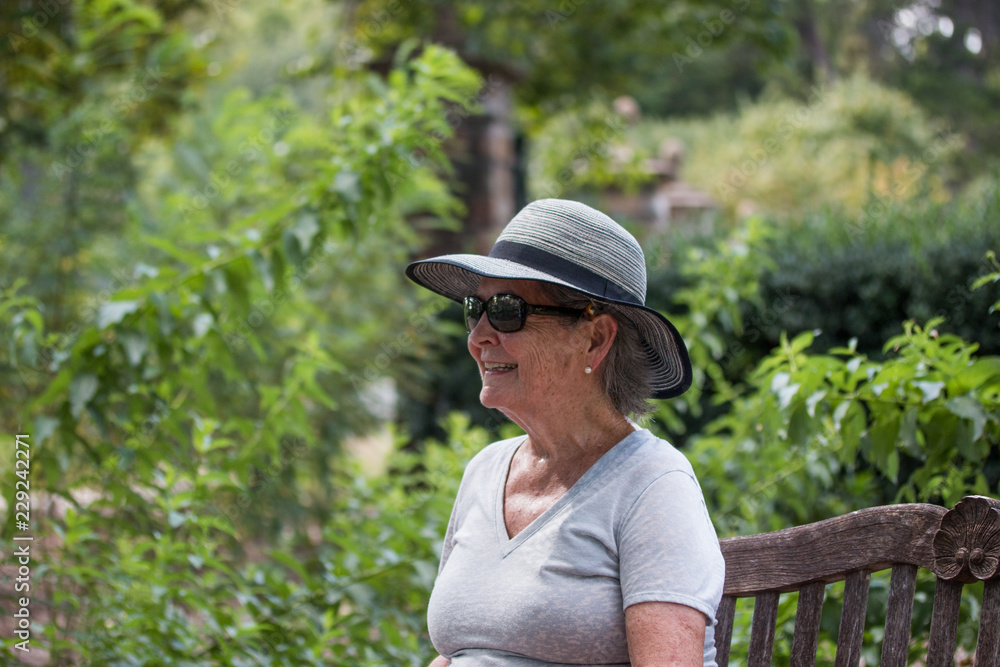 Mature Woman Wearing a Hat Sitting on Park Bench