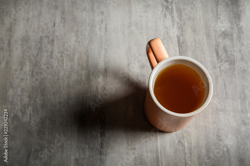 peach-colored cup of tea stands on gray background