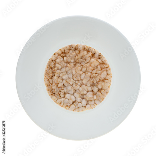 Top view of a single multigrain rice cake on a plate isolated on a white background.