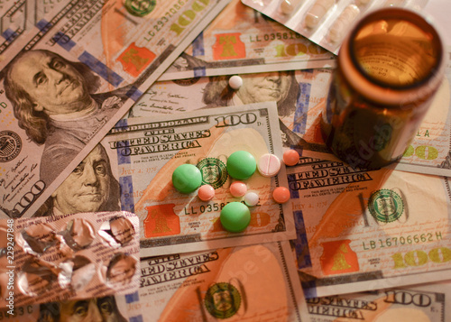 Assorted with medical preparations, pills, capsules, multi-colored vitamins on the background of the image of dollar bills, cash