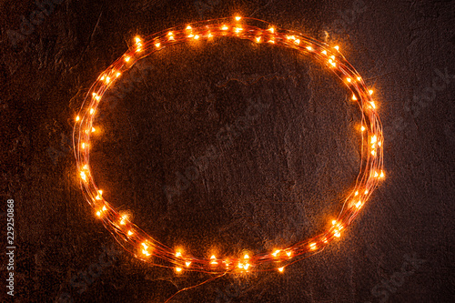 Oval frame of Christmas lights on the black textured wall