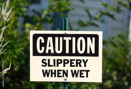 A caution slippery when wet sign on a metal post outside a business. © Bert Folsom