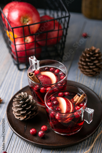 Mulled wine in glasses on a wooden background. Apples, cranberries, cinnamon, star anise, walnuts, cones