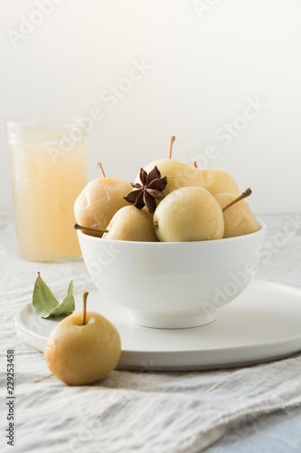 Pickled apples in bowl and apple sidr on white stone table.