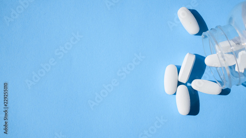 Oxycodone pills. Opioid pain medication, narcotic. Close up white pills with a bottle on a blue background photo