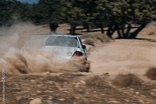 Rally car make a turn with the cloud of sands