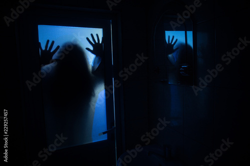 Horror silhouette of woman in window. Scary halloween concept Blurred silhouette of witch in bathroom. Selective focus