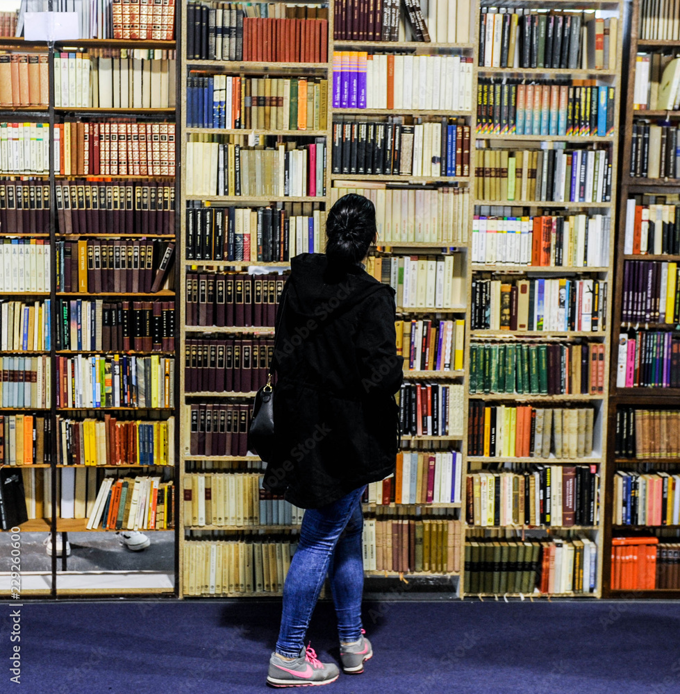 A woman looks at large book shelf A woman looks at large book shelf