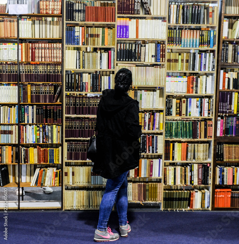 A woman looks at large book shelf