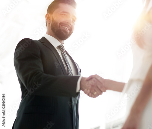 Two business workers shake hands in office