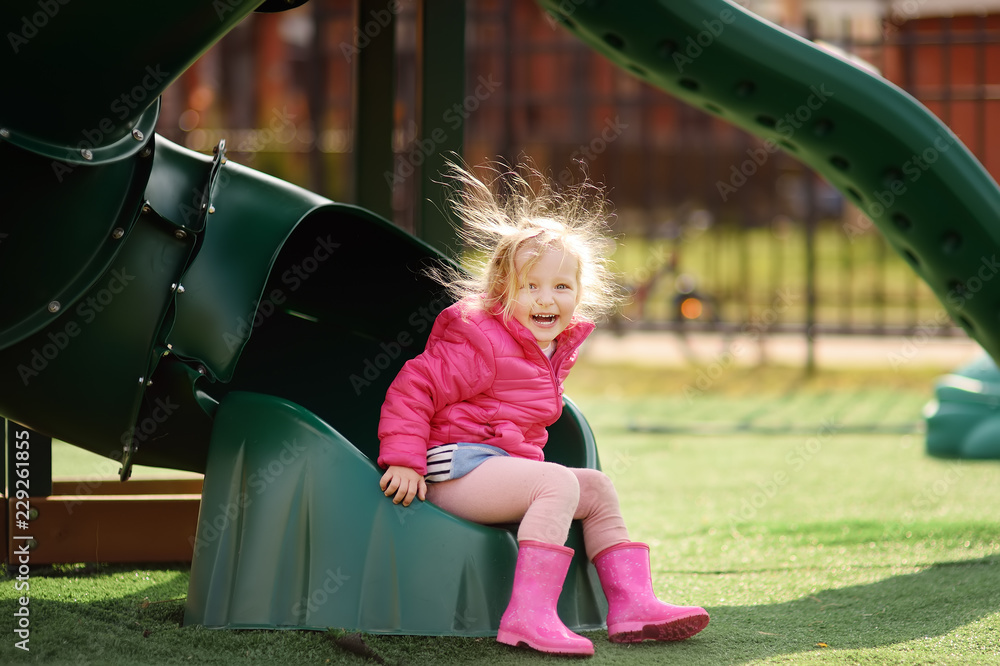 Cute little girl having fun on outdoor playground. Child on plastic slide Stock Photo Adobe Stock