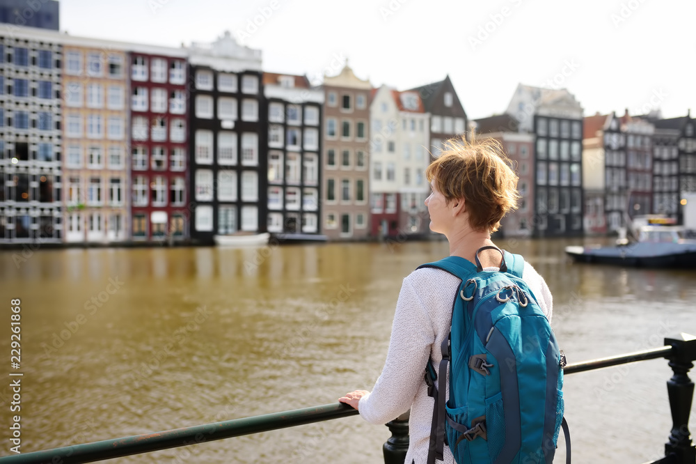 Mature woman looking at the famous dancing houses of Amsterdam on sunny day