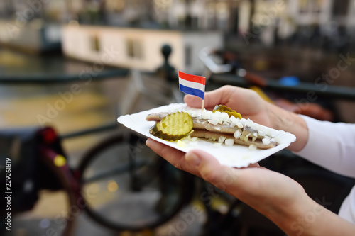 Photography Woman hold plate famous herring fish with onion and cucumber in fastfood market