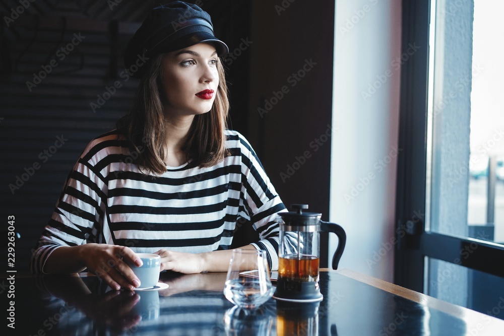 pretty young woman sitting in the cafe with a cup of tea. pretty young woman sitting in the cafe with a cup of tea.