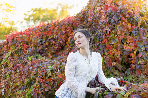 Beautiful girl in a white lace blouse in an autumn park