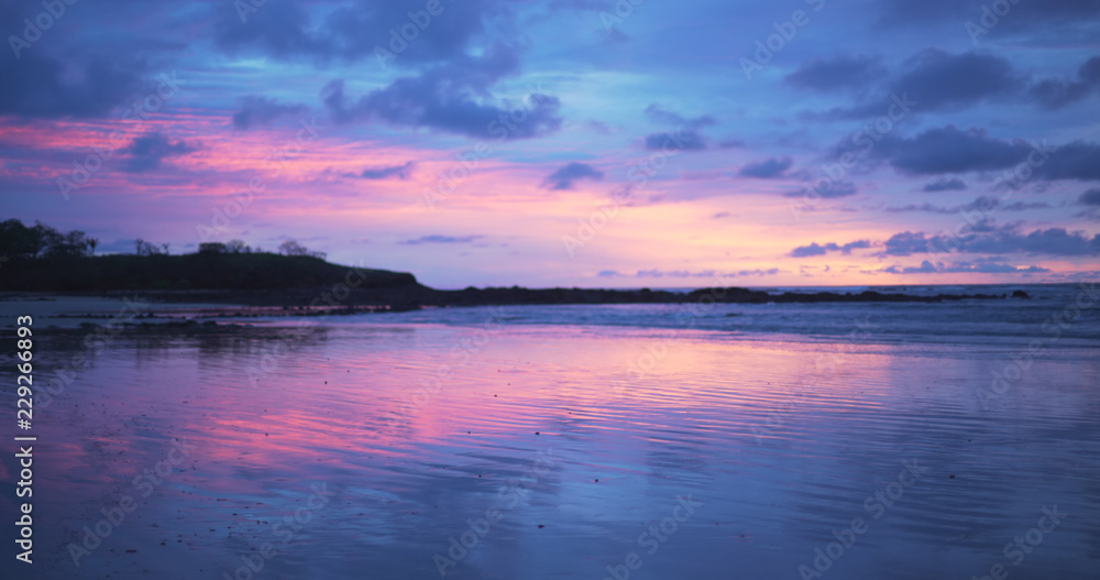 Beautiful out of focus background plate of purple and blue sunset on the beach