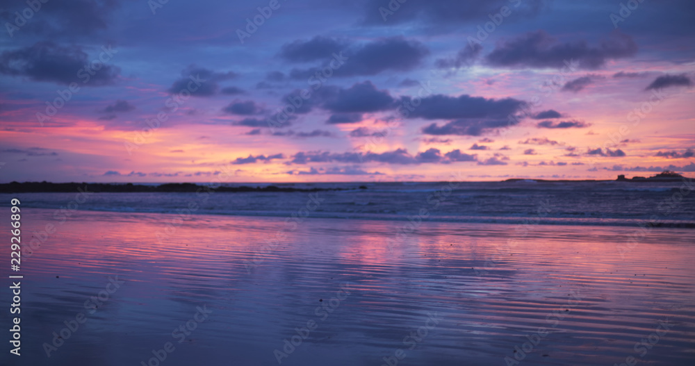 Out of focus background plate of remarkable purple and blue sunset on the beach