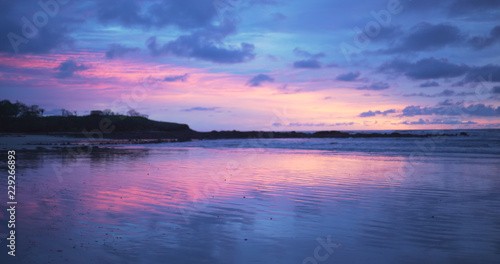 Beautiful out of focus background plate of purple and blue sunset on the beach