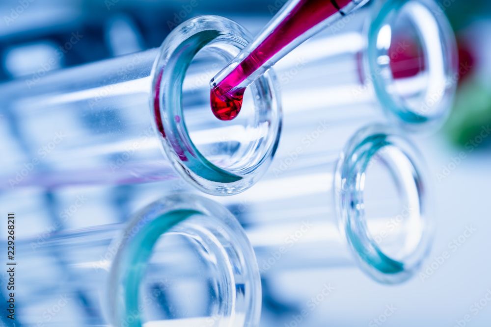 Pipette adding fluid to one of several test tubes .medical glassware Pipette adding fluid to one of several test tubes .medical glassware