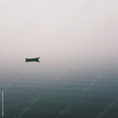 Mistic lonely boat in the middle of the lake  mist fog
