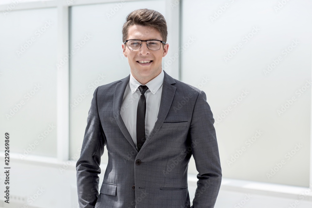 portrait of a young businessman standing near the office window portrait of a young businessman standing near the office window