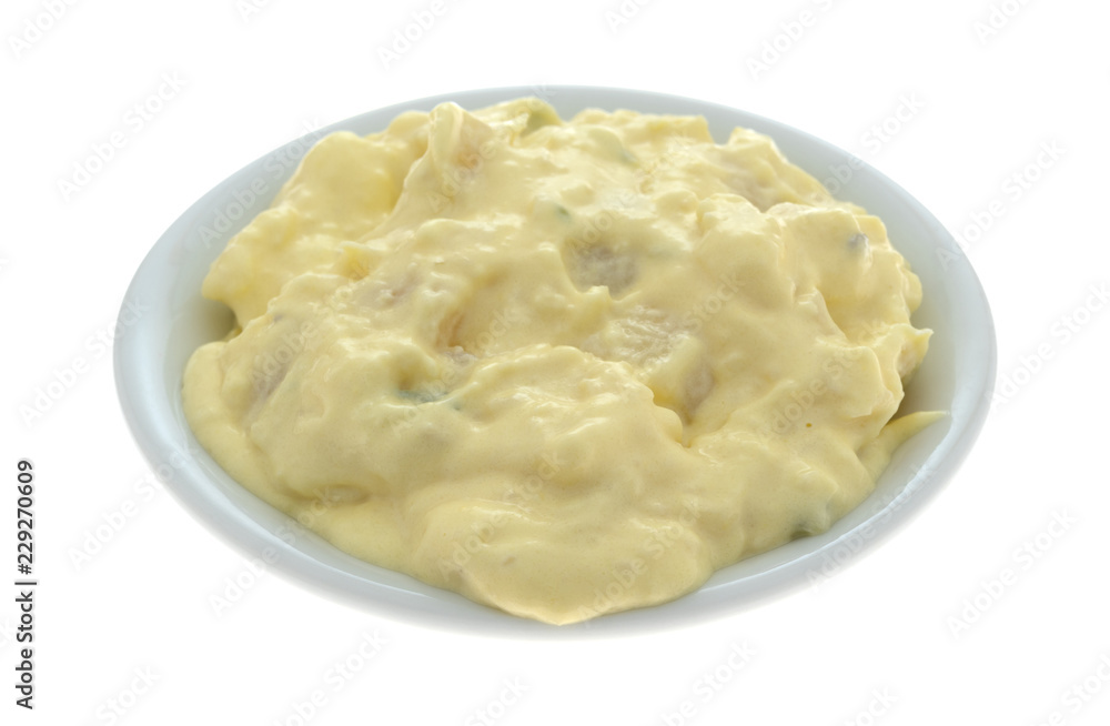 Side view of a portion of potato and egg salad in a small bowl isolated on a white background.