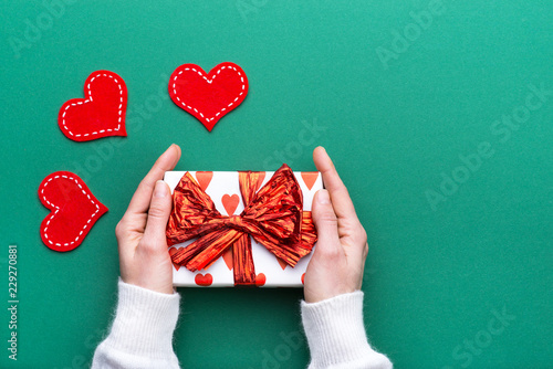 Person holding a present for Saint Valentine's day in his hands. Beautiful colorful background to st. Valentine day. Greeting card with red hearts. Wedding's invitation. Love expression.  photo