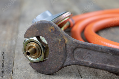 Regulator for propane-butane gas cylinder and accessories on a wooden workshop table. Gas accessories in the workshop.