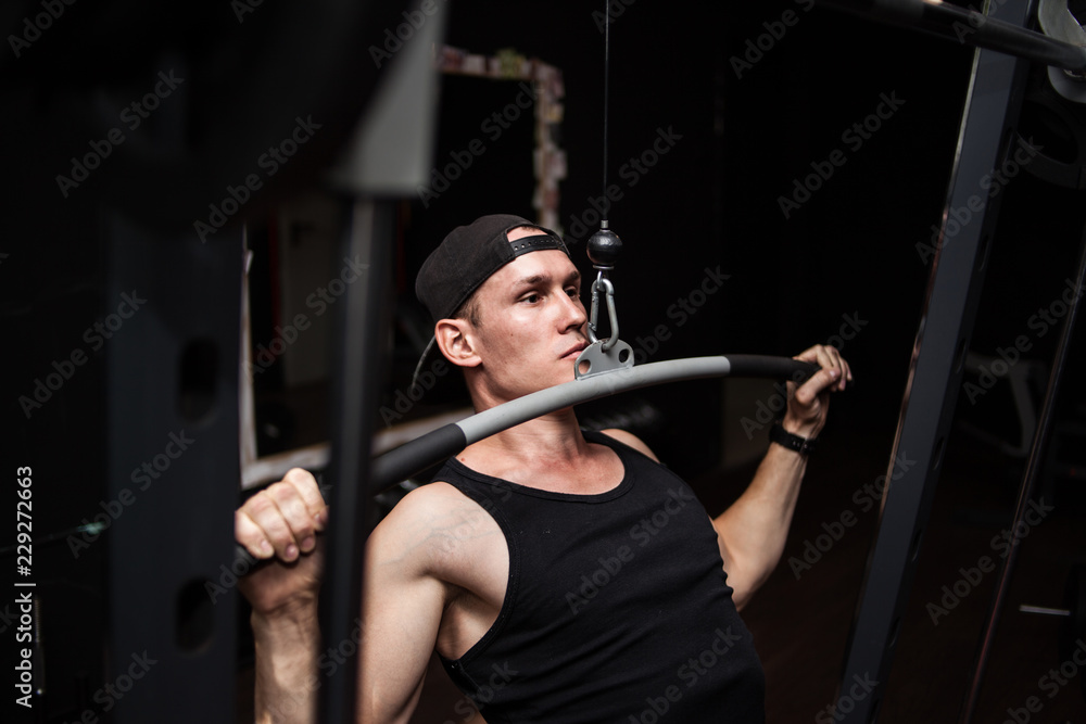 Very powerful athletic guy bodybuilder, exercise for the back and hands. A man in the gym Very powerful athletic guy bodybuilder, exercise for the back and hands. A man in the gym