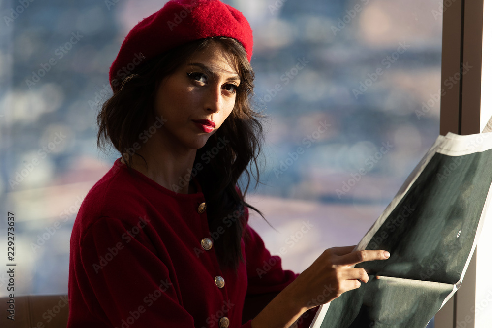 Obraz premium Woman dressed in red fashion reading a newspaper