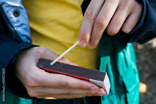 Tourist lights the fire with a matchbox of matches. Concept of safety of children from the threat of fire and parental supervision of explosive substances. Close up © Pavel