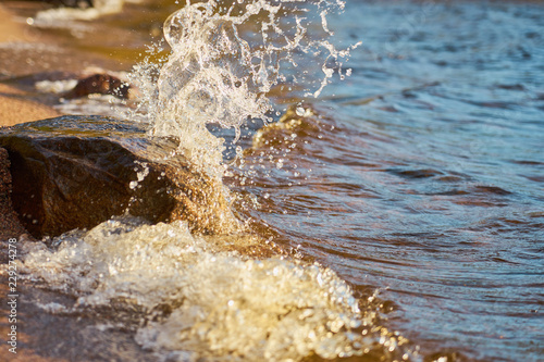                               Water splashing on rock on the beach. © Arthur